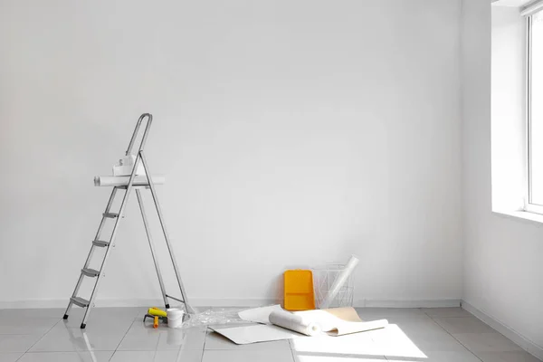 Stock image Wallpaper rolls with supplies and ladder in light room