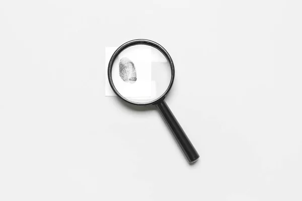 stock image Magnifier and paper with fingerprint on grey background. Detective concept