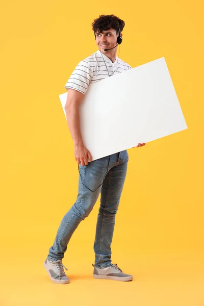 Male technical support agent with blank poster on yellow background