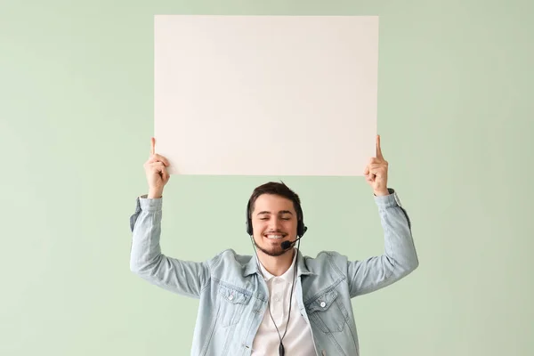 Male technical support agent with blank poster on mint background