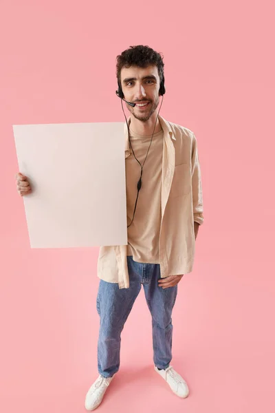 Male technical support agent with blank poster on pink background