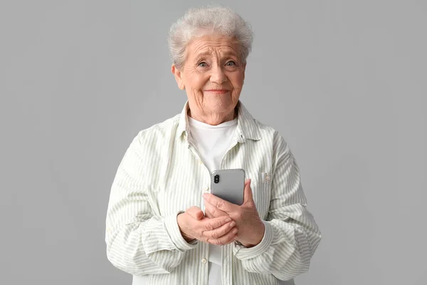 Старшая Женщина Использующая Мобильный Телефон Сером Фоне — стоковое фото