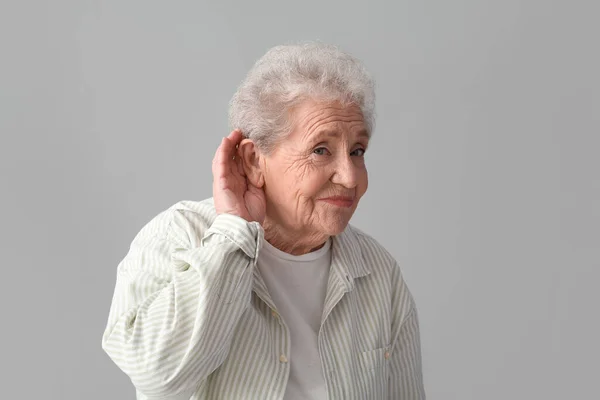 Starsza Kobieta Próbuje Usłyszeć Coś Szarym Tle — Zdjęcie stockowe