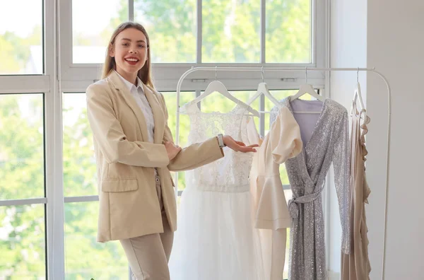 Female wedding planner with dresses working in office