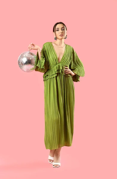 ファッショナブルな美しいです女性でスタイリッシュな緑のドレスとともにディスコボールポーズピンクの背景 — ストック写真