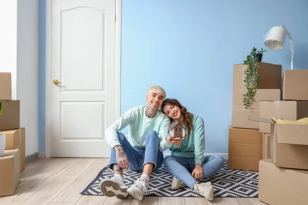 Young couple with house model in room on moving day