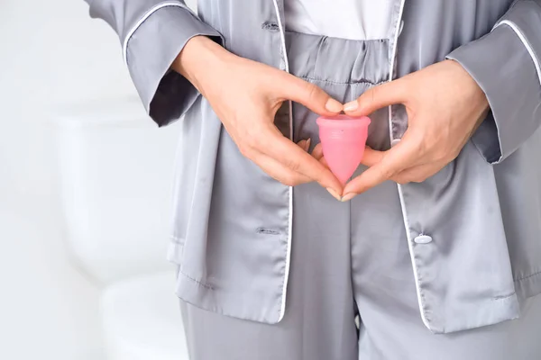 Copo menstrual branco com corações vermelhos simbolizando a menstruação em  rosa