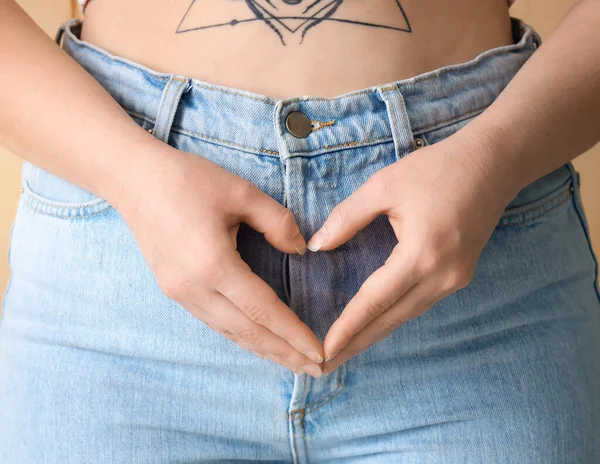 Junge Frau Mit Menstruationskrämpfen Macht Herzgeste Auf Beigem Hintergrund Nahaufnahme — Stockfoto