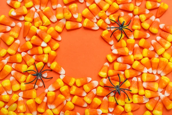 おいしいハロウィーンのキャンディーコーンとオレンジ色の背景のクモで作られたフレーム — ストック写真