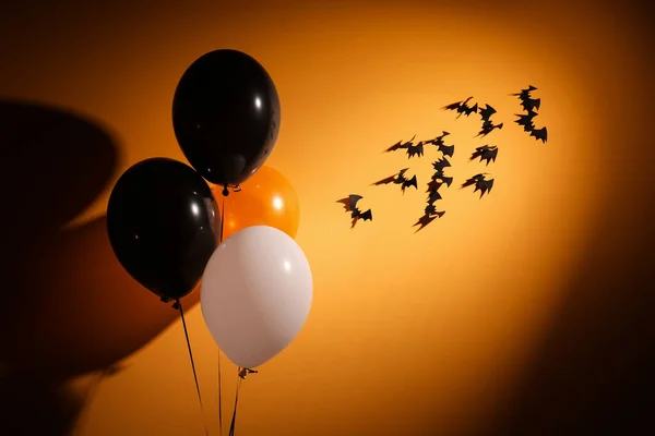 Halloween balloons and bats hanging on orange wall in room