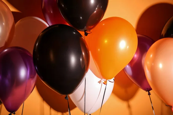 Different Halloween balloons on orange background, closeup