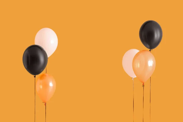 Different Halloween balloons on orange background