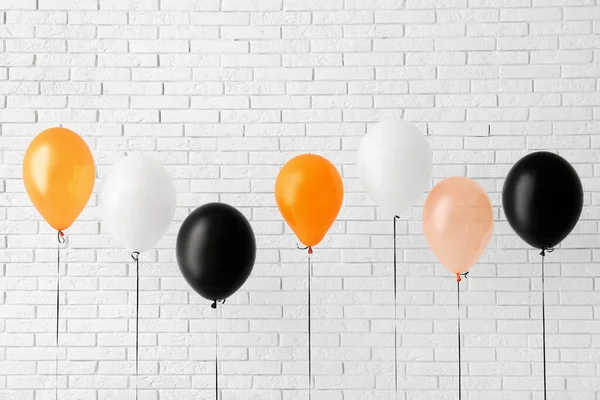 stock image Different Halloween balloons near light brick wall in room