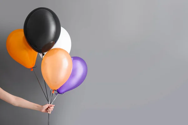 Weibliche Hand Mit Verschiedenen Halloween Luftballons Auf Grauem Hintergrund — Stockfoto