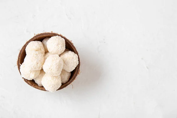 stock image Coconut shell with white chocolate candies on light table