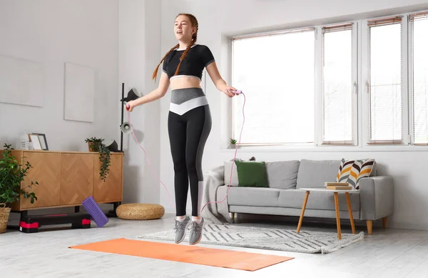 Sporty young woman jumping with rope at home