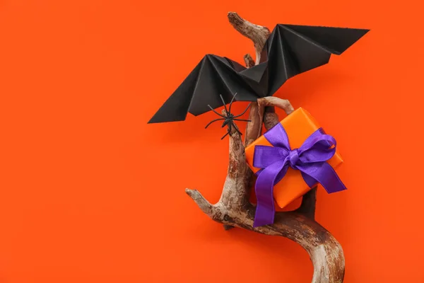 Composition with wood, bat and gift box for Halloween on orange background