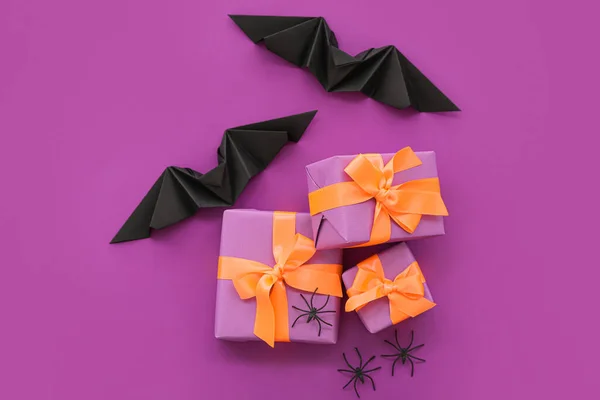 Composition with spiders, bats and gift boxes for Halloween on purple background