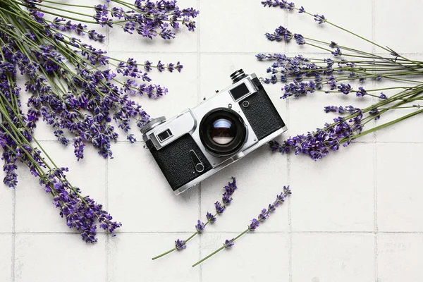 stock image Beautiful lavender flowers and photo camera on light tile background