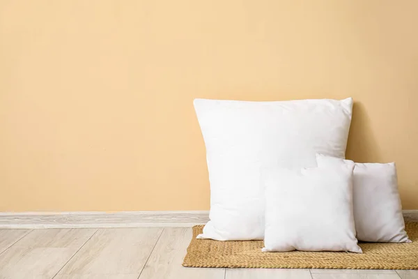 米色墙边柳条垫子上的白色枕头 — 图库照片