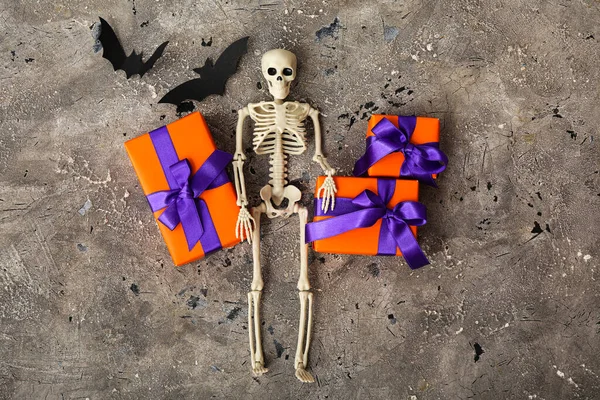 Beautiful gift boxes, bats and skeleton for Halloween on grey grunge background