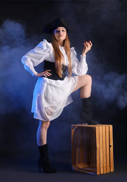 stock image Beautiful female pirate with smoking pipe on black background