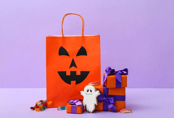 stock image Composition with shopping bag, cookie, gift boxes and tasty candies for Halloween on purple background