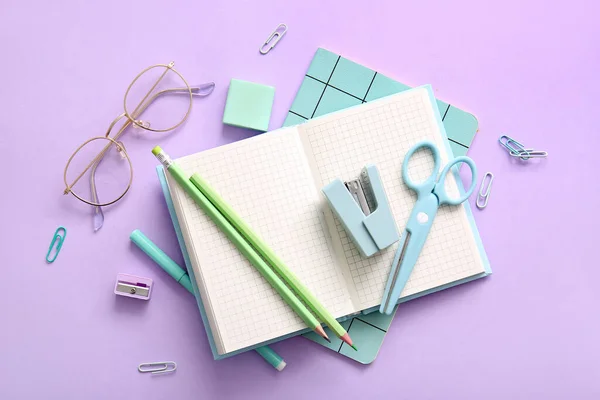 紫色背景的不同学校文具 笔记本和眼镜 — 图库照片