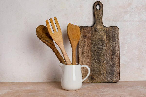Pitcher with wooden cutlery and cutting board on table