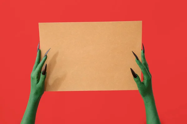 Groene Handen Van Heks Met Blanco Vel Papier Rode Achtergrond — Stockfoto