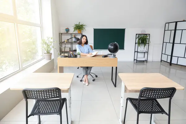 教室でテーブルで書く女性アジアの教師 — ストック写真