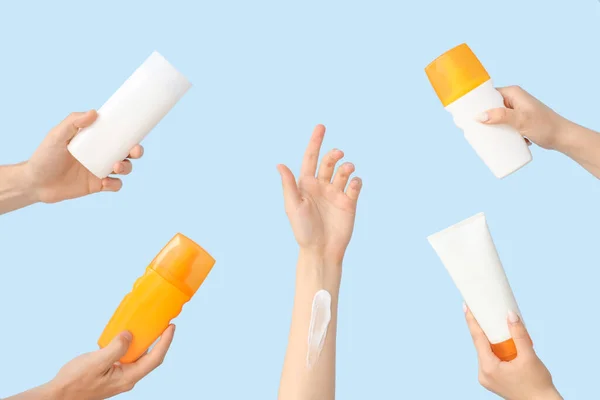 Female hands with bottles of sunscreen cream on blue background