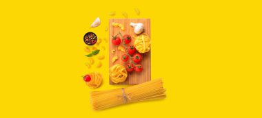 Sarı zemin üzerinde farklı türde makarna, baharat ve domates.