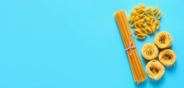 Açık mavi zemin üzerinde değişik tipte kuru makarna, metin için boşluk, üst görünüm