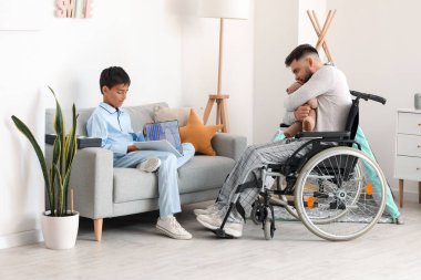 Küçük çocuk ve babası tekerlekli sandalyede evde oyuncaklarla