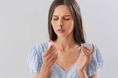 Burnu kanayan ve arka planda doku olan genç bir kadın.