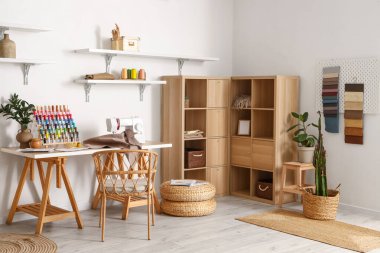 Interior of modern atelier with tailor's workplace, thread spools and shelves