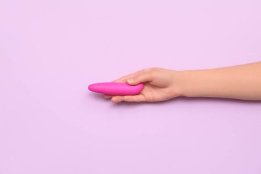 Leylak arka planında seks dükkanından pembe vibratörü olan kadın.