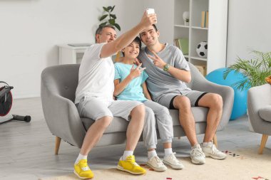 Mutlu küçük çocuk babasıyla ve dedesiyle evde selfie çekiyor.