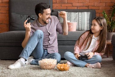Babası ve küçük kızı evde video oyunu oynuyorlar.
