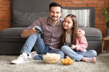 Babası ve küçük kızı evde video oyunu oynuyorlar.