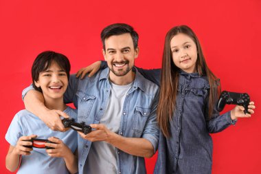 Kırmızı arka planda babalarıyla oyun oynayan küçük çocuklar.