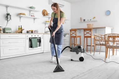 Mutfakta halı süpüren genç bir kadın.