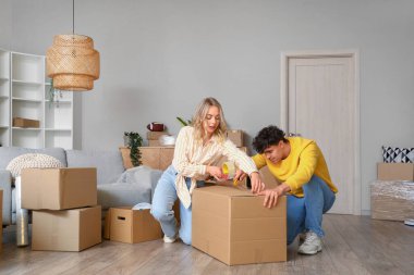 Genç çift taşınma gününde odada karton kutu kaydediyor.