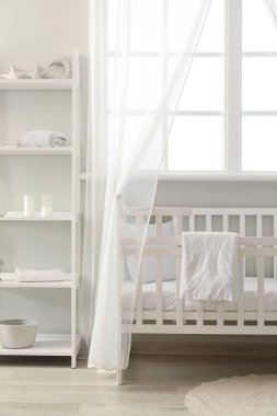 Şık çocuk odasının içinde beşik ve raf ünitesi var.