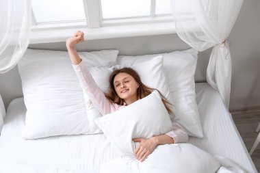 Güzel genç bir bayanın yumuşak yatağında, manzaralı bir sabah.