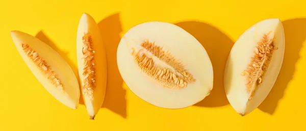Pieces of sweet ripe melon on yellow background, top view
