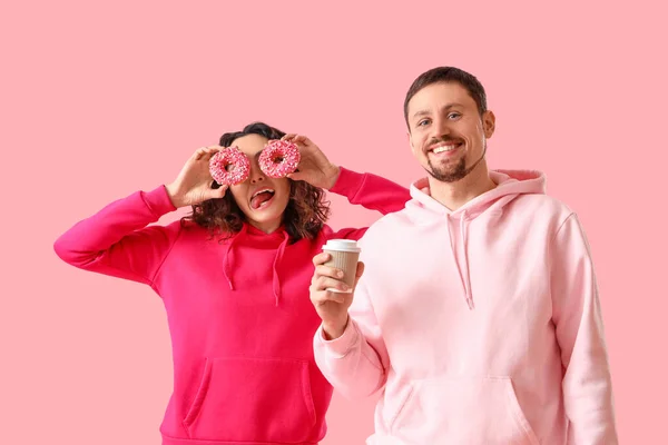 Casal Jovem Com Saborosos Donuts Xícara Café Fundo Rosa — Fotografia de Stock