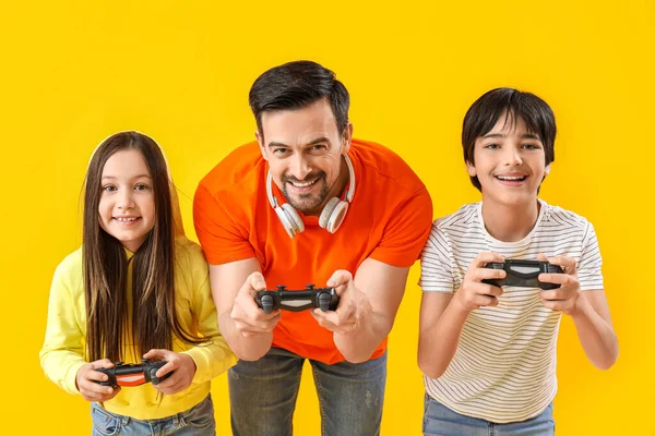 Padre Con Sus Hijos Pequeños Jugando Videojuegos Sobre Fondo Amarillo — Foto de Stock