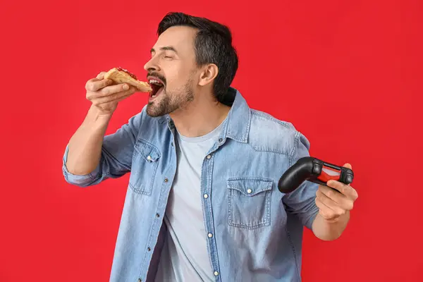 Schöner Mann Mit Spielkissen Beim Pizza Essen Auf Rotem Hintergrund — Stockfoto